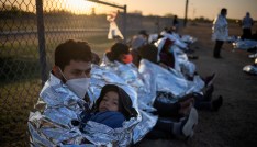 Dustin, an asylum-seeking migrant from Honduras, holds his six-year-old son Jerrardo, 6, as they awake at sunrise next to others who took refuge near a baseball field after crossing the Rio Grande river into the United States from Mexico on rafts, in La Joya, Texas, U.S., March 19, 2021. Emergency blankets were provided to the group of about 150 migrants from Central America by the U.S. Border Patrol agents. REUTERS/Adrees Latif     TPX IMAGES OF THE DAY